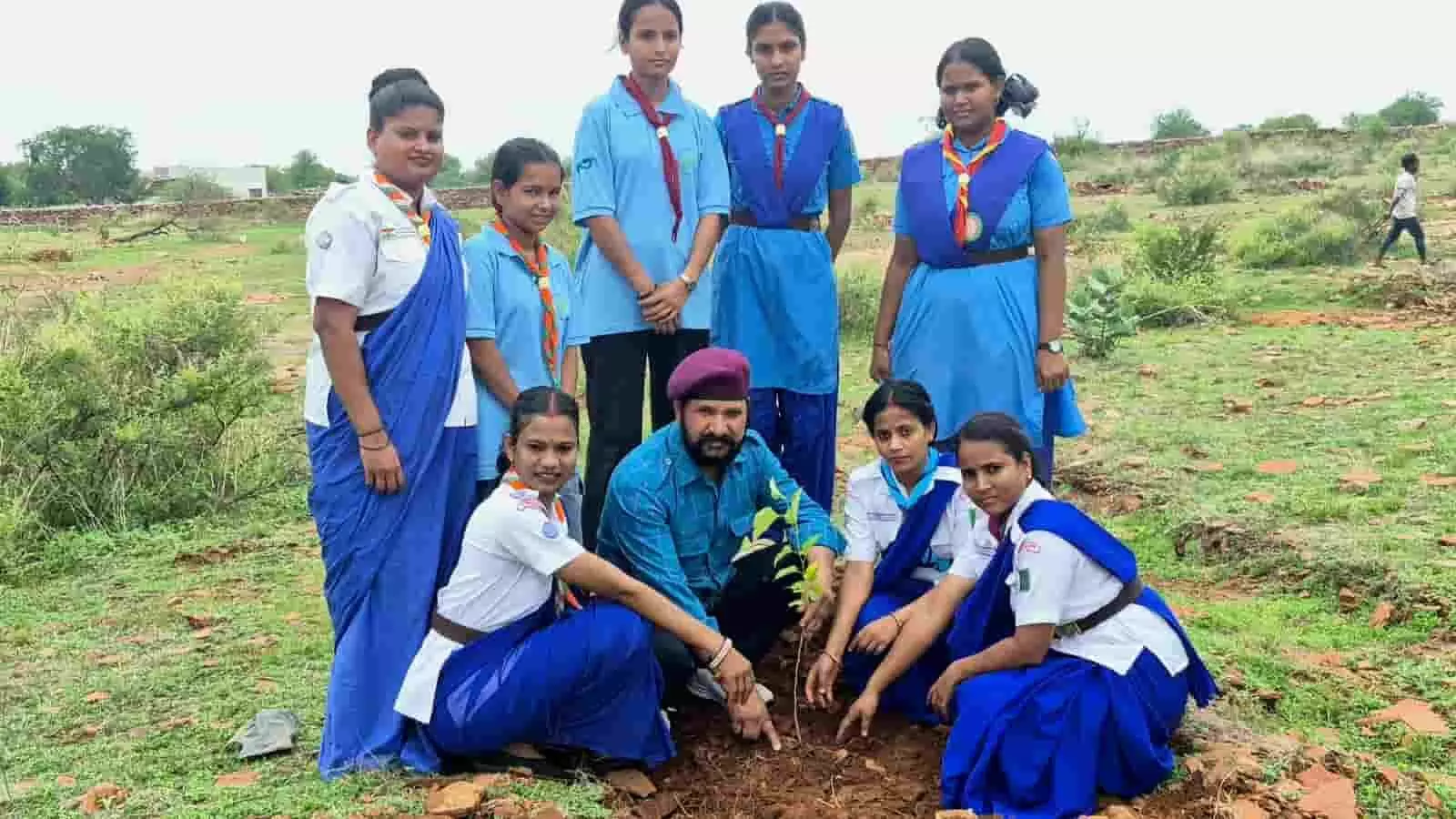 तस्वीर में खुले मैदान में स्काउट-गाइड यूनीफॉर्म पहने लोग पौधा लगाते हुए दिख रहे हैं। तस्वीर में खुले मैदान में स्काउट-गाइड यूनीफॉर्म पहने लोग पौधा लगाते हुए दिख रहे हैं।