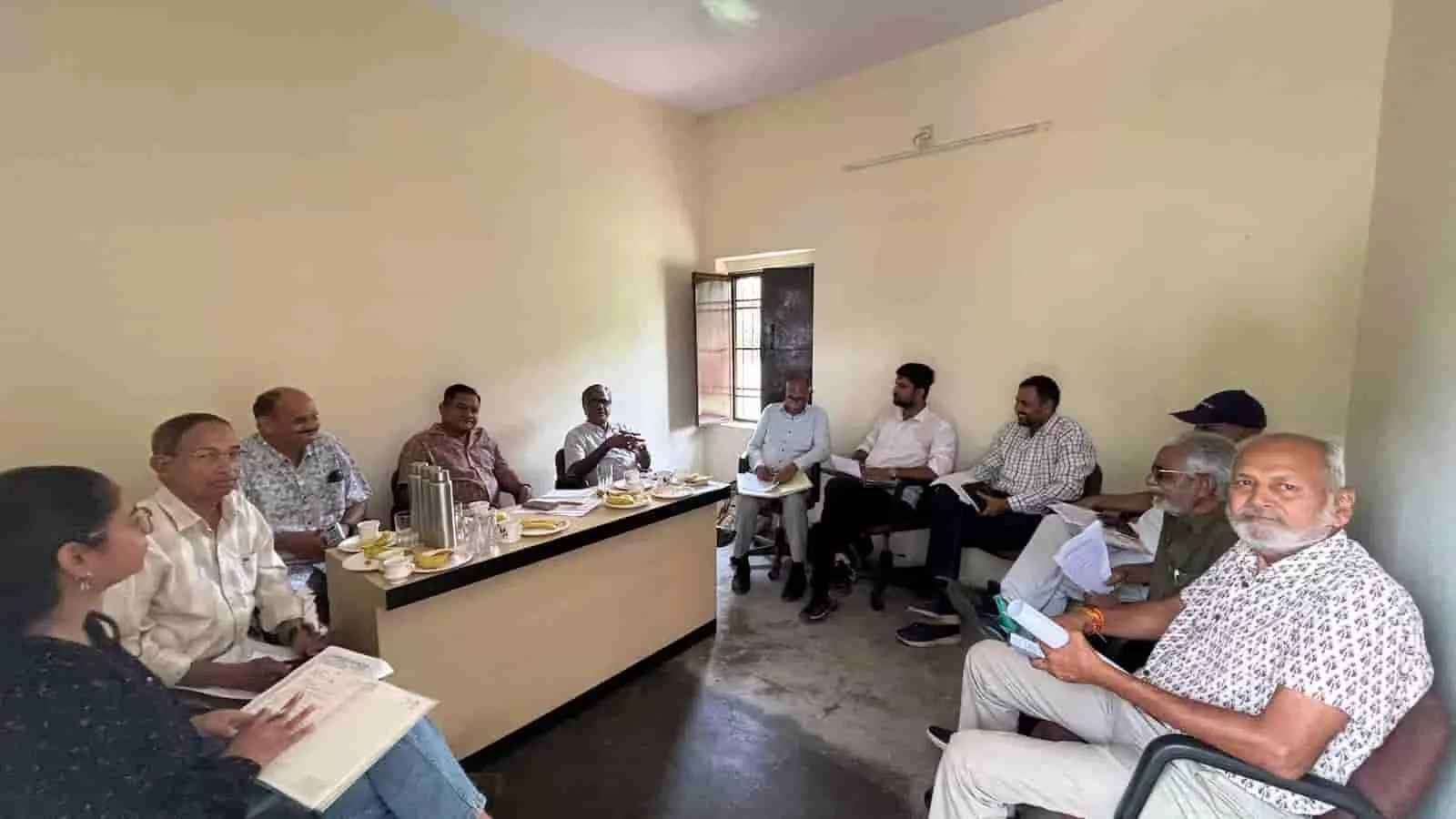 बैठक कक्ष में मेज के पास कुर्सियों पर बैठकर चर्चा करते ग्रीन पीपल सोसायटी के सदस्य।