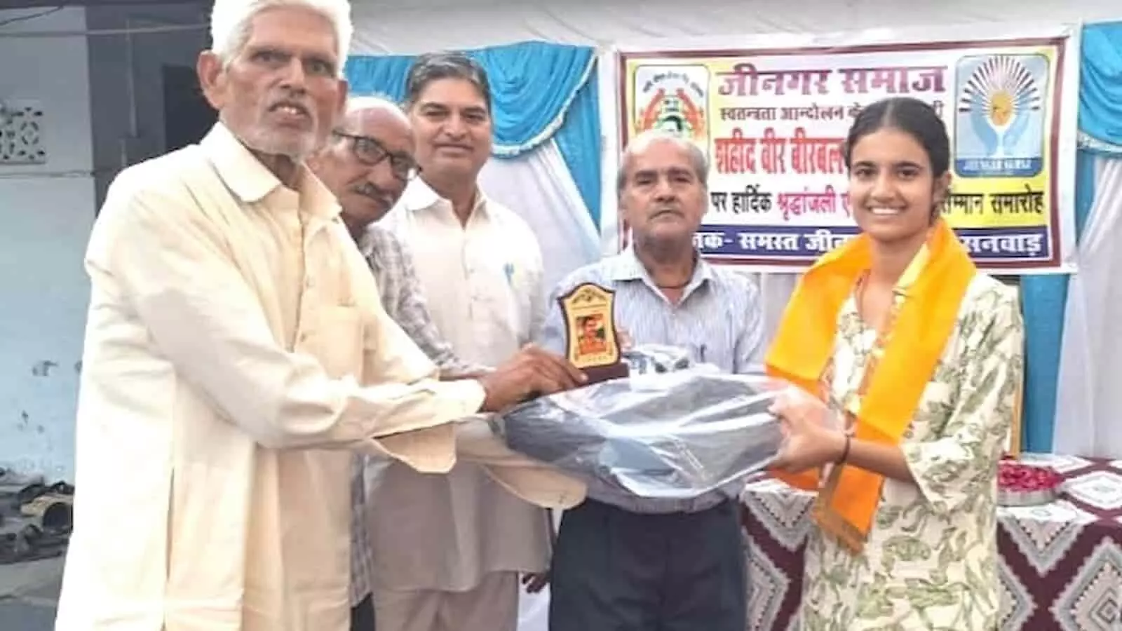 तस्वीर में जीनगर समाज के वरिष्ठ सदस्य एक छात्रा को स्मृति चिह्न देकर सम्मानित कर रहे हैं।