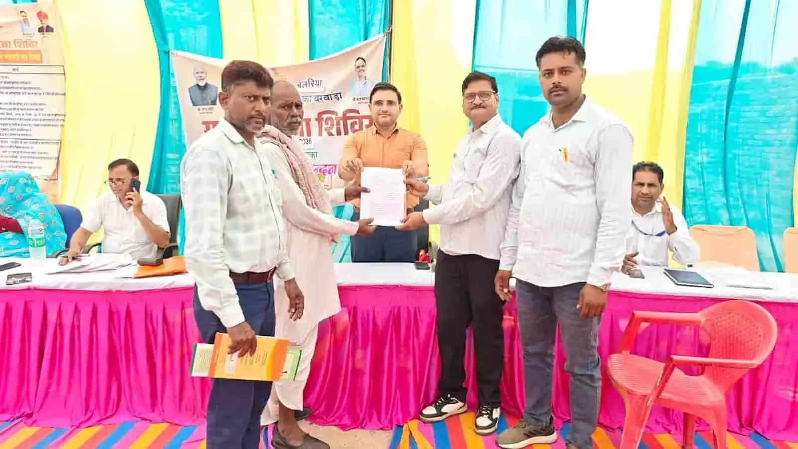 सवाई माधोपुर में सरकारी शिविर के दौरान अधिकारी किसान को दस्तावेज सौंप रहे हैं। सवाई माधोपुर में सरकारी शिविर के दौरान अधिकारी किसान को दस्तावेज सौंप रहे हैं।