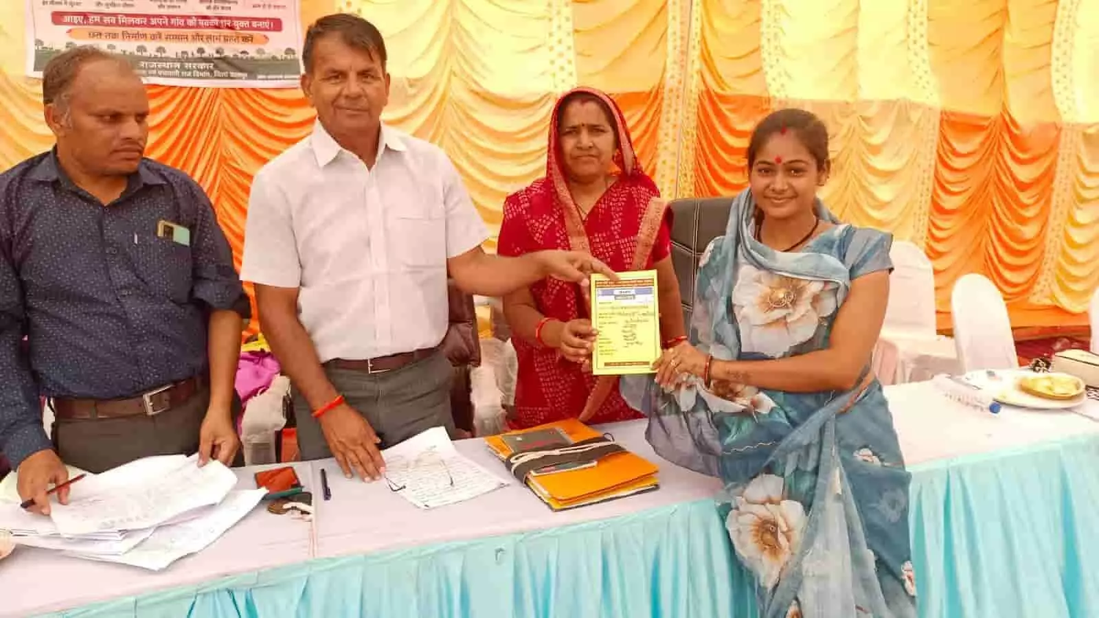 खेरवाड़ा में अधिकारी एक महिला को सरकारी दस्तावेज प्रदान कर रहे हैं।