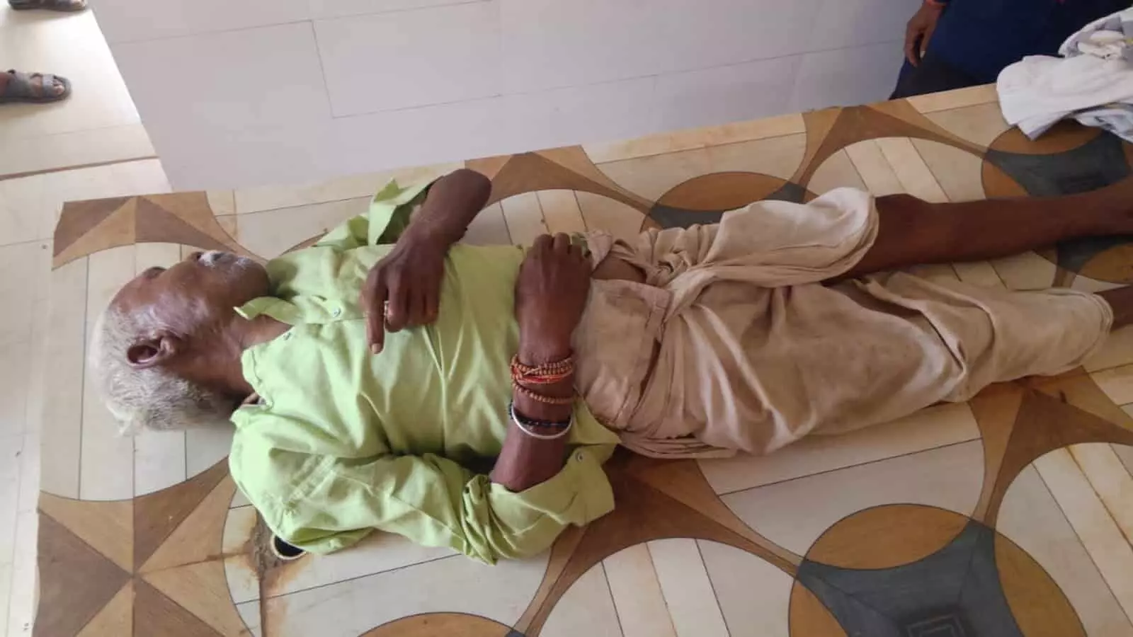 फर्श पर लेटे हुए एक बुजुर्ग व्यक्ति का दृश्य कटनी के संदर्भ में।