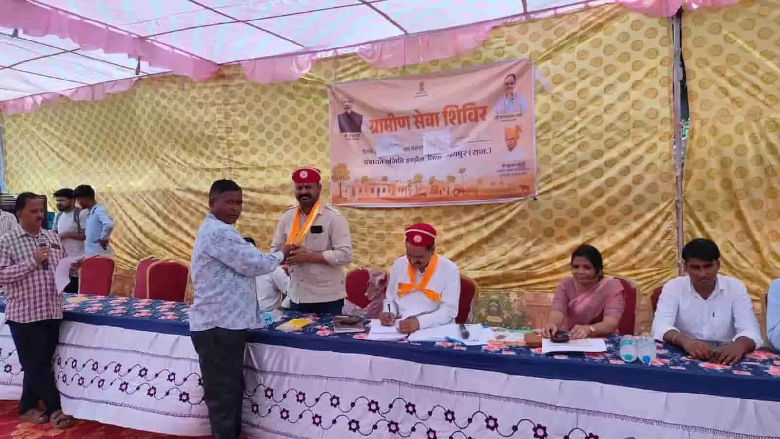 उपरेटा में आयोजित ग्रामीण सेवा शिविर के दौरान मंच पर बैठे अधिकारी और जनप्रतिनिधि।