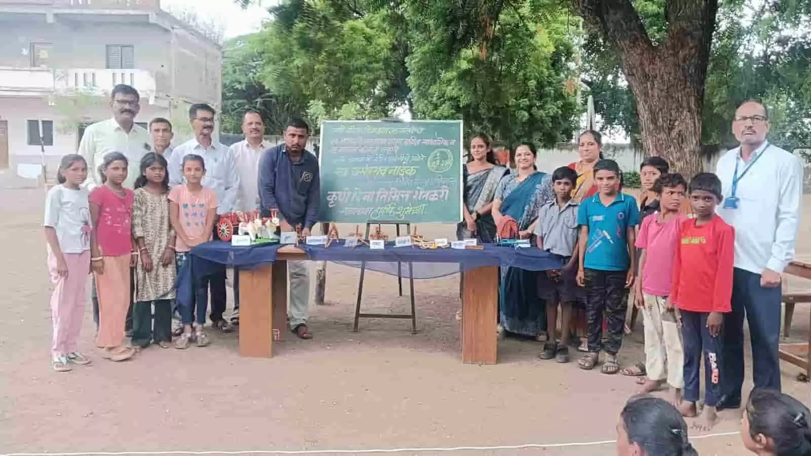 स्कूल मैदान में कृषि दिवस प्रदर्शनी के दौरान पारंपरिक औजारों के साथ खड़े शिक्षक और बच्चे। स्कूल मैदान में कृषि दिवस प्रदर्शनी के दौरान पारंपरिक औजारों के साथ खड़े शिक्षक और बच्चे।