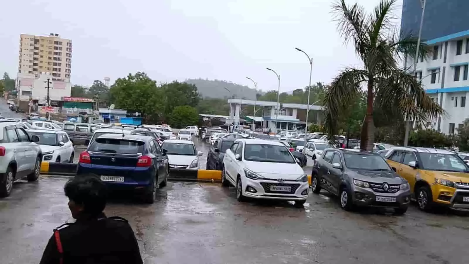 बारिश के बाद खुले परिसर में खड़ी कारें और पृष्ठभूमि में बादलों से घिरे पहाड़। बारिश के बाद खुले परिसर में खड़ी कारें और पृष्ठभूमि में बादलों से घिरे पहाड़।