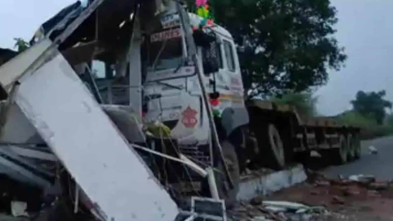 तस्वीर में एक क्षतिग्रस्त ट्रक सड़क किनारे ढहे हुए कंक्रीट केबिन के मलबे के पास खड़ा दिख रहा है।