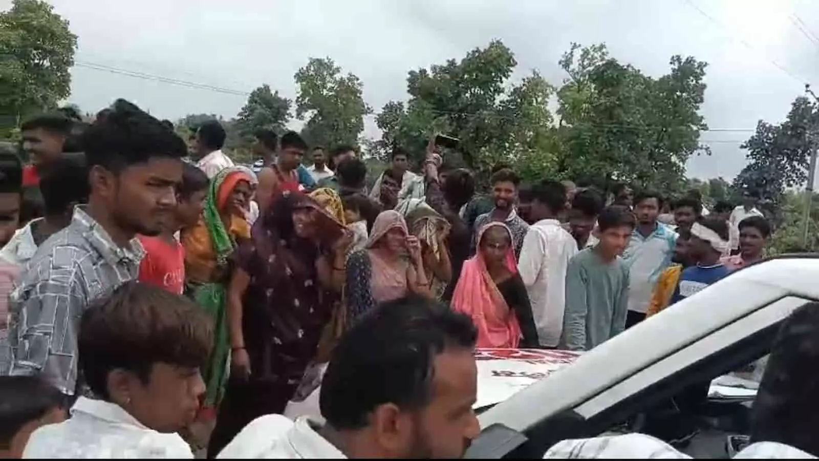 केना गांव की सड़क पर एक वाहन के चारों तरफ खड़े ग्रामीण भीड़ के रूप में दिख रहे हैं। केना गांव की सड़क पर एक वाहन के चारों तरफ खड़े ग्रामीण भीड़ के रूप में दिख रहे हैं।
