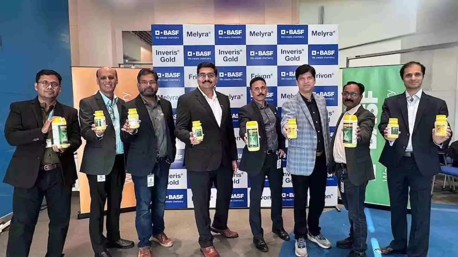 बैनर के सामने खड़े आठ पुरुष हाथ में पीले डिब्बे प्रदर्शित कर रहे हैं। बैनर के सामने खड़े आठ पुरुष हाथ में पीले डिब्बे प्रदर्शित कर रहे हैं।