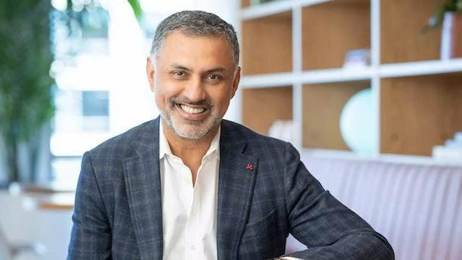 तस्वीर में निकेश अरोड़ा एक औपचारिक सूट पहने मेज के पास बैठे हैं। तस्वीर में निकेश अरोड़ा एक औपचारिक सूट पहने मेज के पास बैठे हैं।