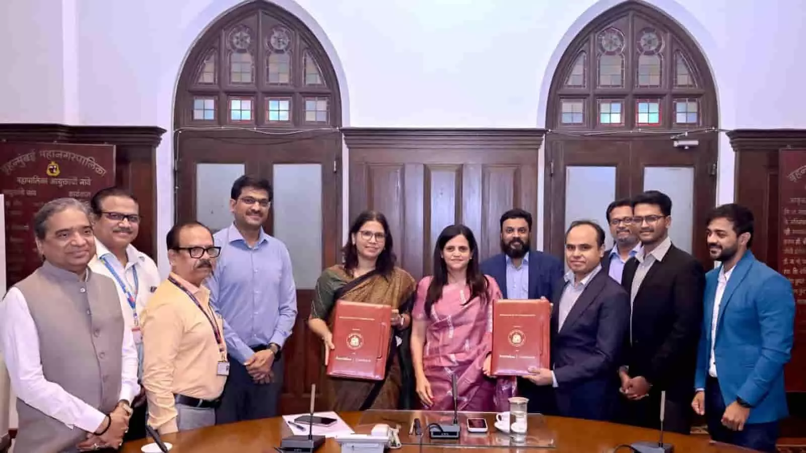 तस्वीर में बीएमसी मुख्यालय के भीतर अधिकारी और प्रतिनिधि हाथ में एमओयू दस्तावेज लेकर खड़े दिख रहे हैं। तस्वीर में बीएमसी मुख्यालय के भीतर अधिकारी और प्रतिनिधि हाथ में एमओयू दस्तावेज लेकर खड़े दिख रहे हैं।
