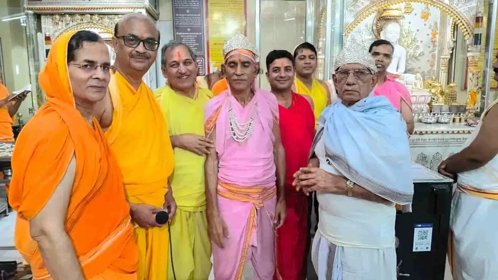 मंदिर के अंदर पारंपरिक वस्त्र और माला पहने पुरुषों का समूह खड़े होकर तस्वीर खिंचवाता हुआ।