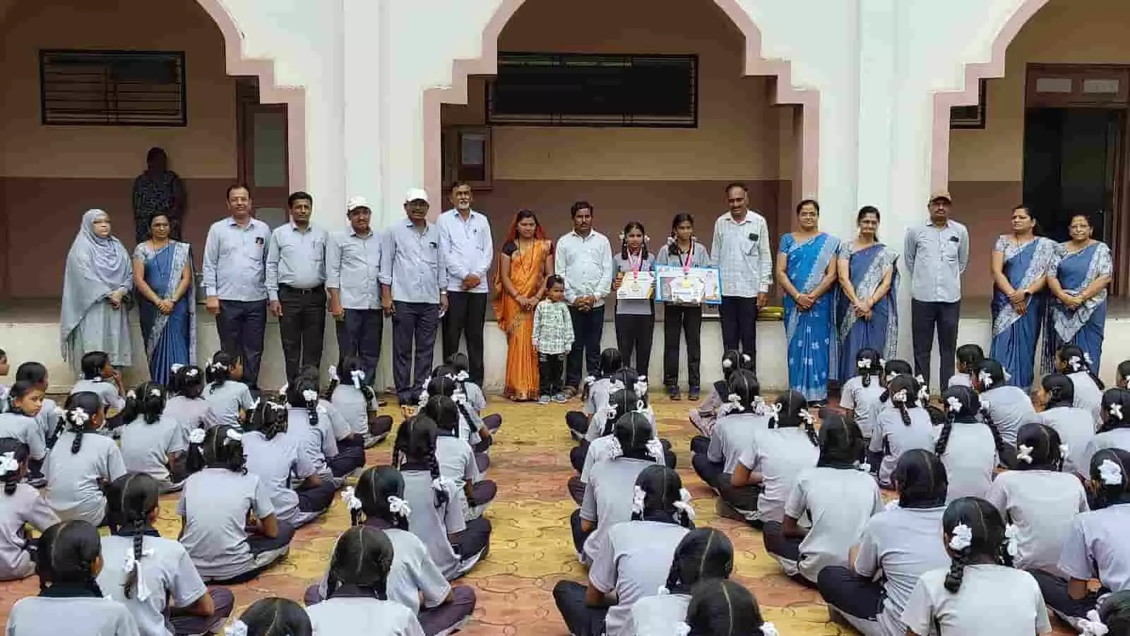 स्कूल परिसर में आयोजित कार्यक्रम के दौरान सम्मानित छात्राओं और शिक्षकों के साथ उपस्थित अन्य लोग।