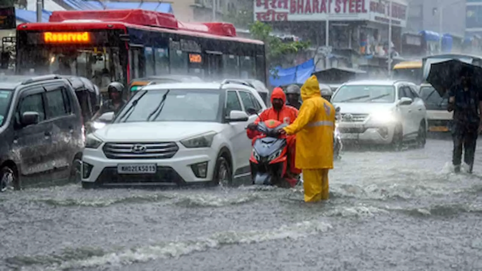 मुंबई की बारिश में जलभराव वाली सड़क पर वाहन और रेनकोट पहने व्यक्ति दिख रहे हैं। मुंबई की बारिश में जलभराव वाली सड़क पर वाहन और रेनकोट पहने व्यक्ति दिख रहे हैं।