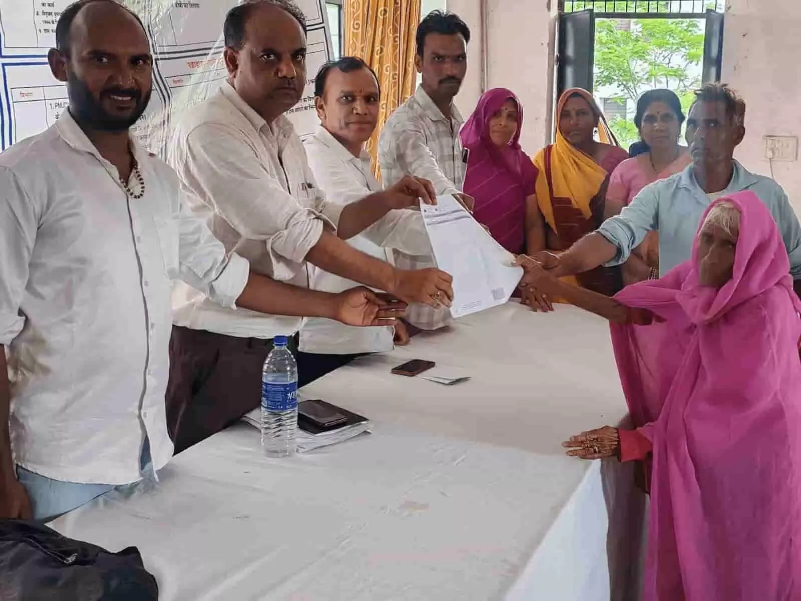 : तस्वीर में अधिकारी बिजयपुर में एक ग्रामीण महिला को सरकारी दस्तावेज सौंप रहे हैं। : तस्वीर में अधिकारी बिजयपुर में एक ग्रामीण महिला को सरकारी दस्तावेज सौंप रहे हैं।