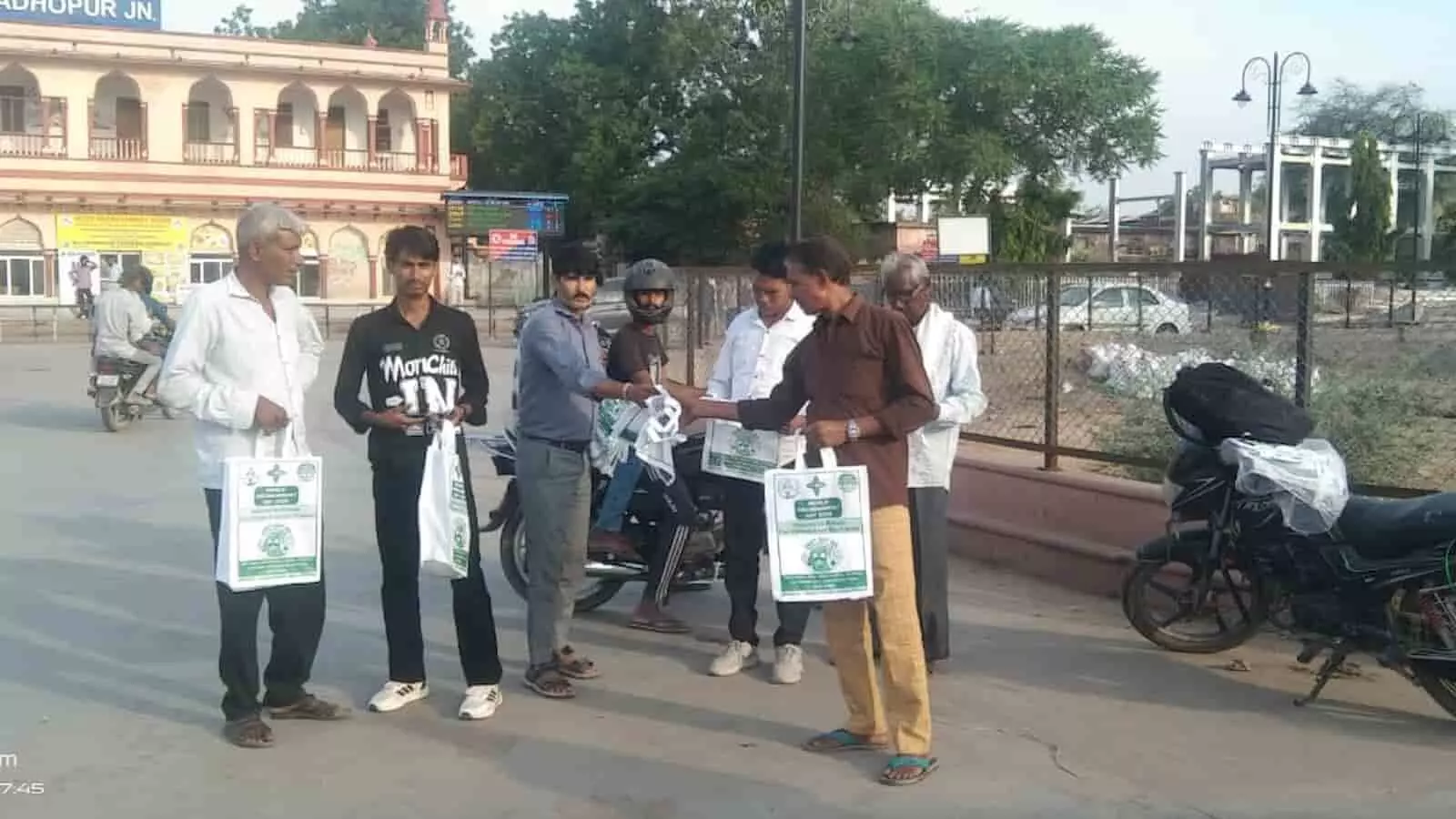तस्वीर में लोग सवाई माधोपुर रेलवे स्टेशन के बाहर नागरिकों को कपड़े के थैले वितरित करते दिख रहे हैं।