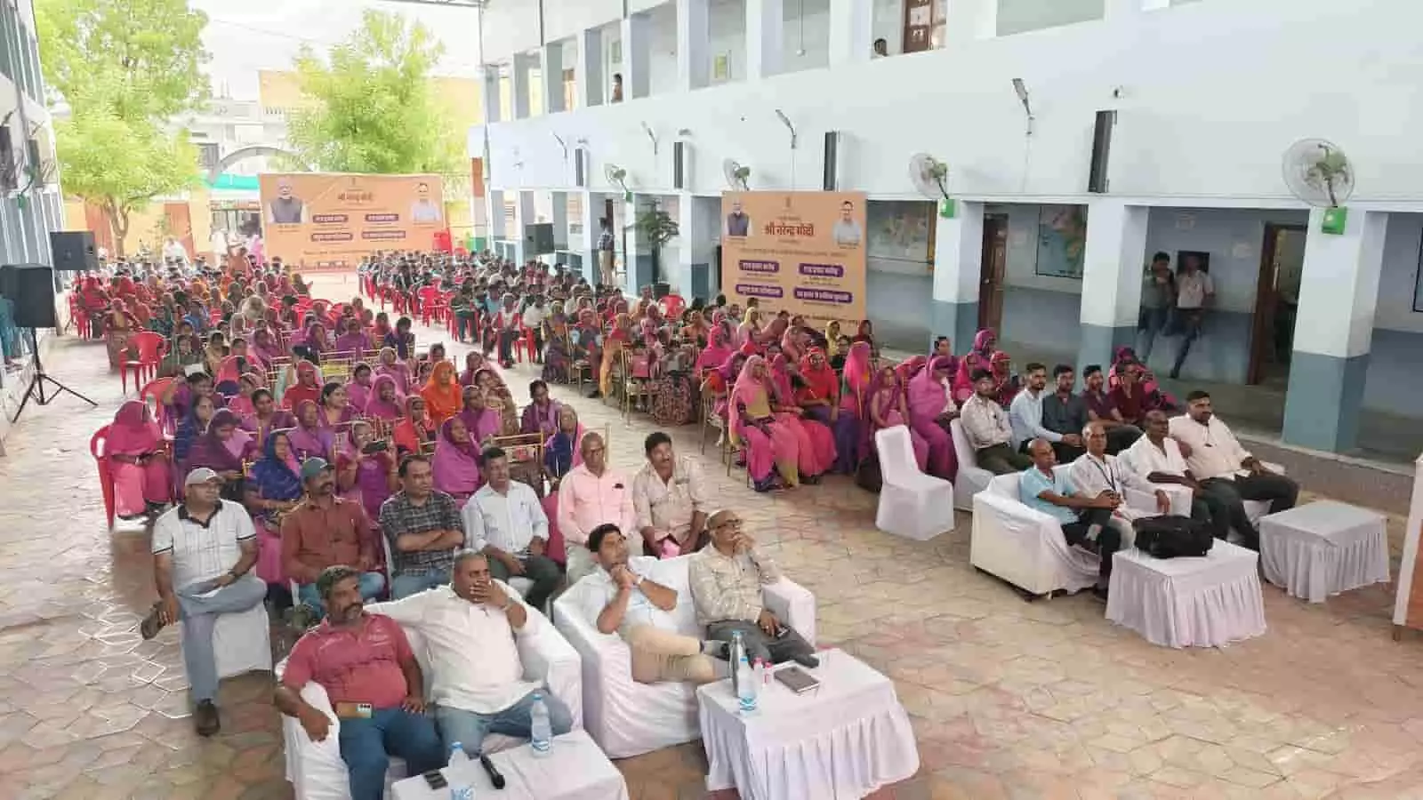 स्कूल परिसर में कुर्सियों पर बैठकर लाइव प्रसारण देखते ग्रामीण और अधिकारी। स्कूल परिसर में कुर्सियों पर बैठकर लाइव प्रसारण देखते ग्रामीण और अधिकारी।