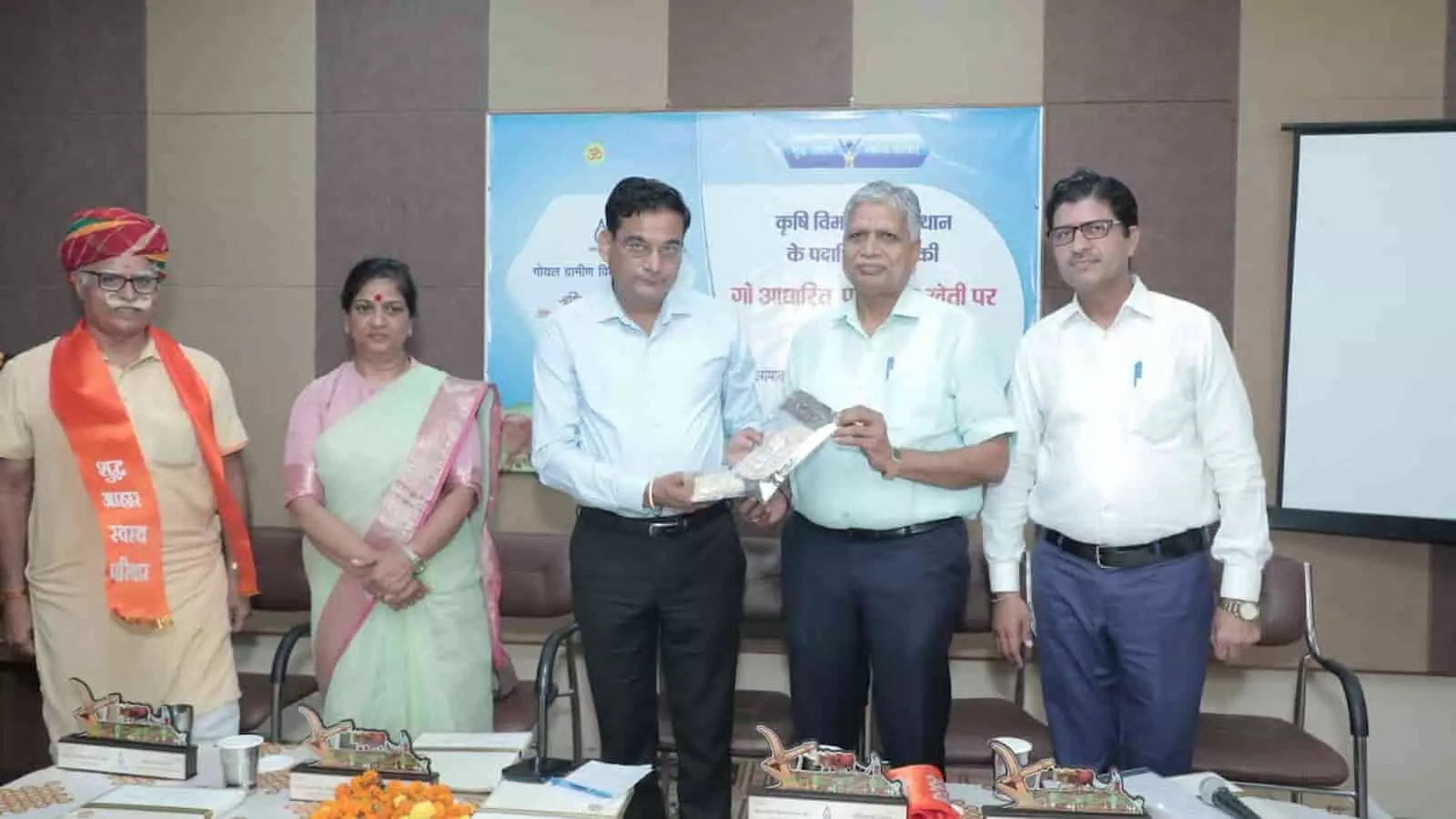 तस्वीर में कृषि आयुक्त अन्य अधिकारियों के साथ एक बैठक में खड़े हैं।