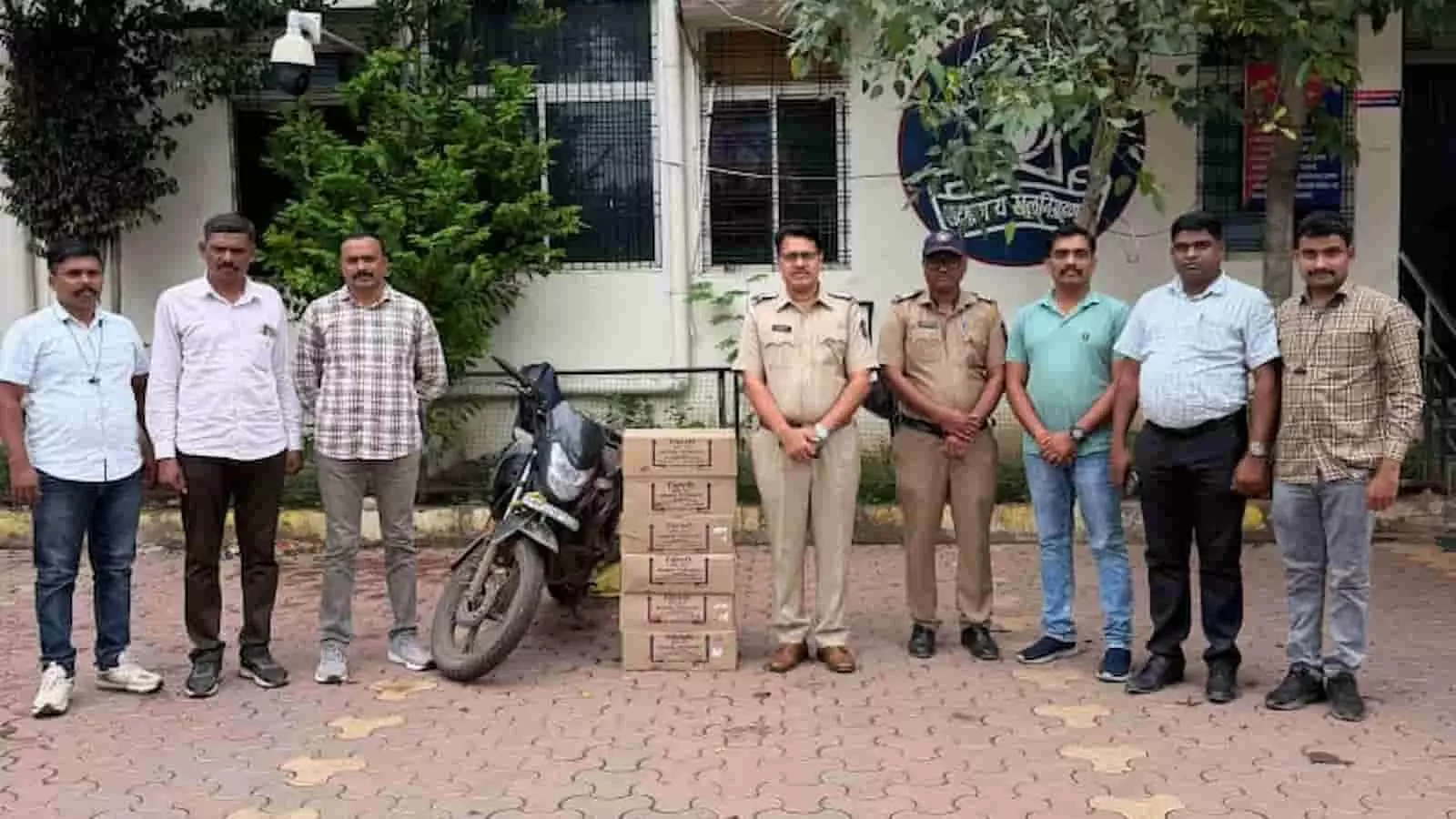 पुलिस स्टेशन के बाहर खड़े अधिकारी और ज़ब्त की गई बाइक और कार्टन बॉक्स