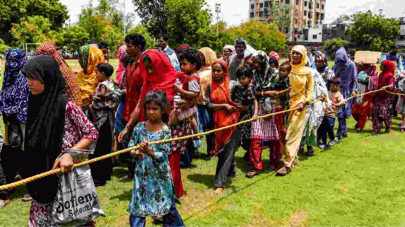 एक रस्सी के सहारे कतार में चलते विदेशी नागरिक डिटेंशन सेंटर से निकलते हुए दिखाई दे रहे हैं। एक रस्सी के सहारे कतार में चलते विदेशी नागरिक डिटेंशन सेंटर से निकलते हुए दिखाई दे रहे हैं।