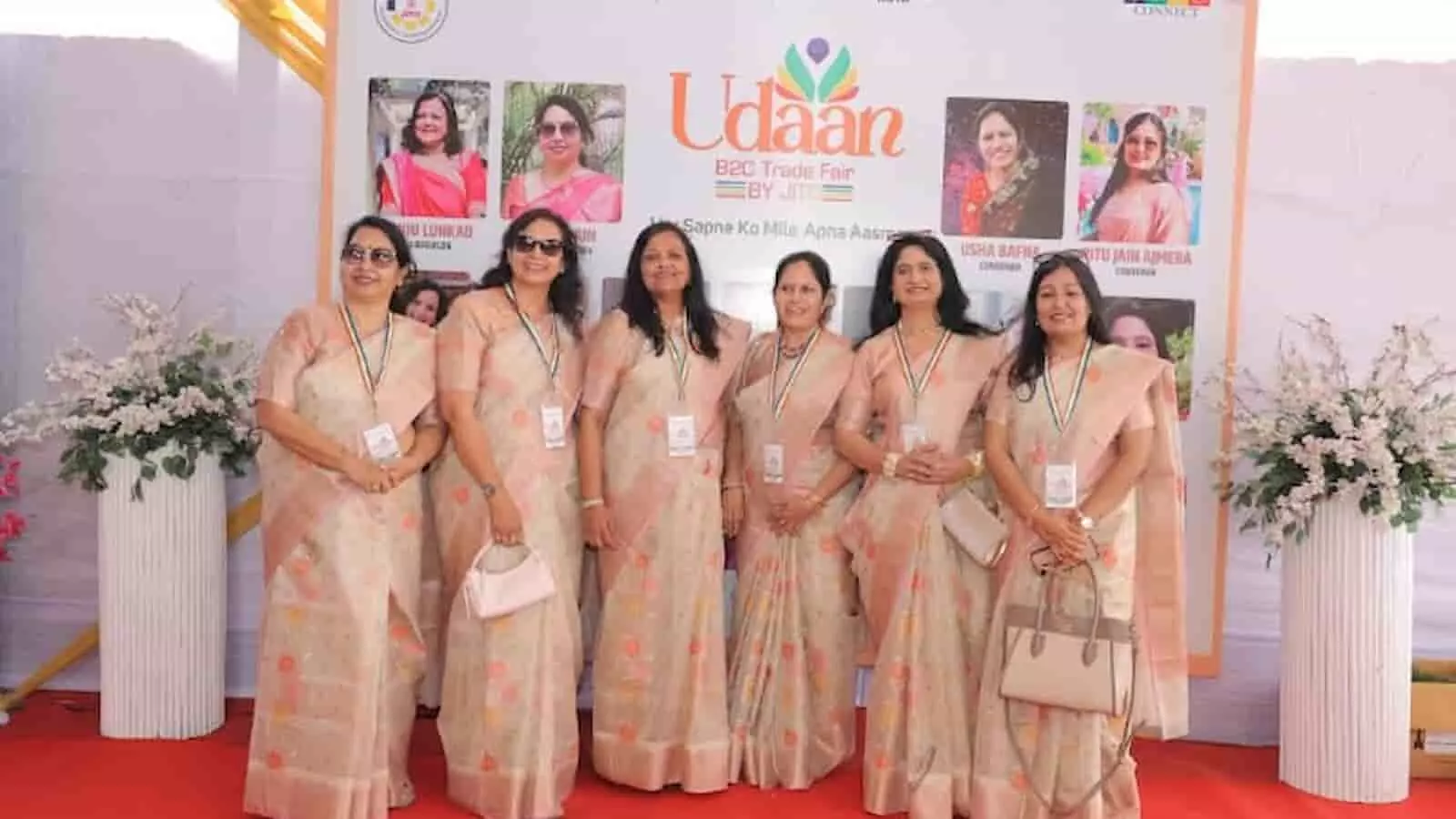 उड़ान एक्ज़िबिशन के बैनर के सामने पारंपरिक साड़ियों में खड़ीं जीतो लेडीज विंग की महिला पदाधिकारी।