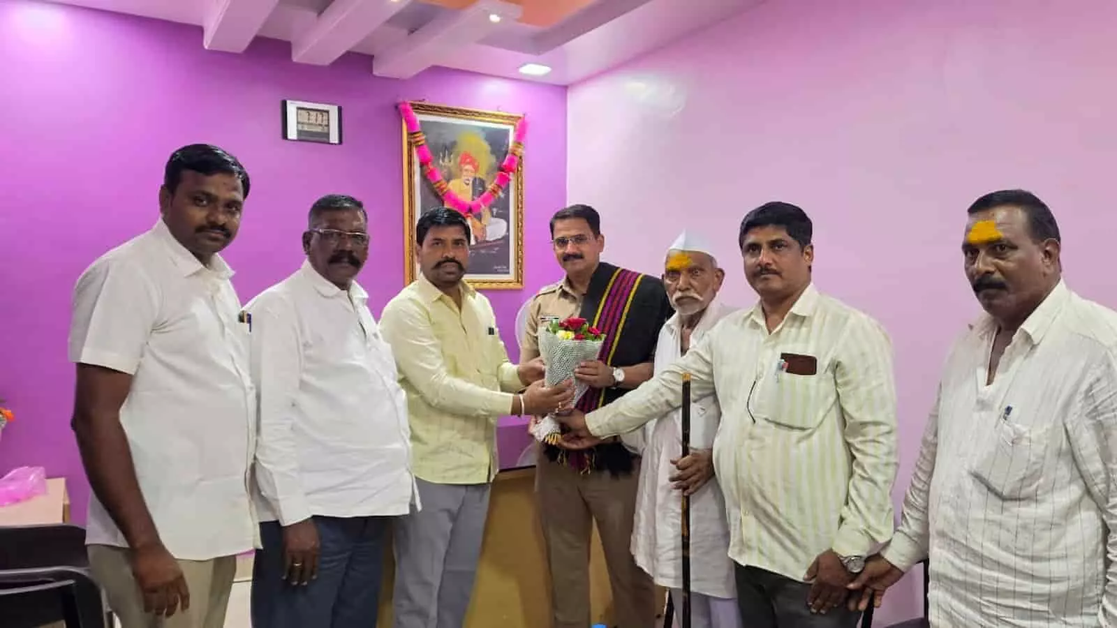 तस्वीर में कई लोग एक कक्ष में पुलिस अधिकारी को पुष्पगुच्छ भेंट करते दिख रहे हैं। तस्वीर में कई लोग एक कक्ष में पुलिस अधिकारी को पुष्पगुच्छ भेंट करते दिख रहे हैं।