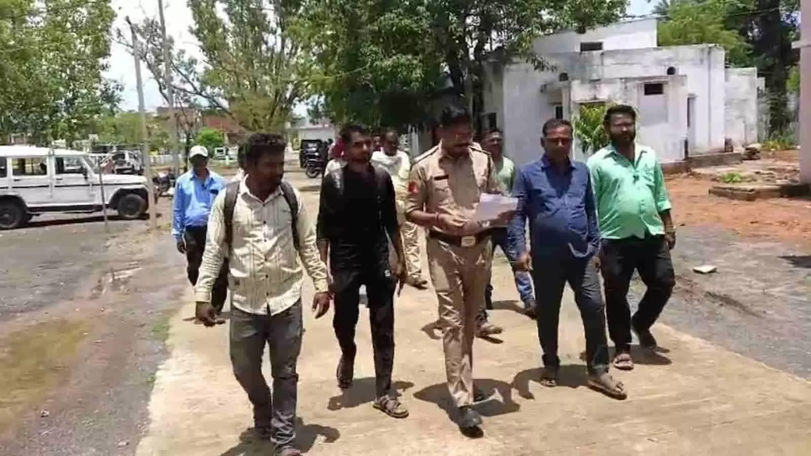 तस्वीर में एक पुलिस अधिकारी और कुछ नागरिक खुले परिसर में पैदल चलते हुए दिखाई दे रहे हैं। तस्वीर में एक पुलिस अधिकारी और कुछ नागरिक खुले परिसर में पैदल चलते हुए दिखाई दे रहे हैं।