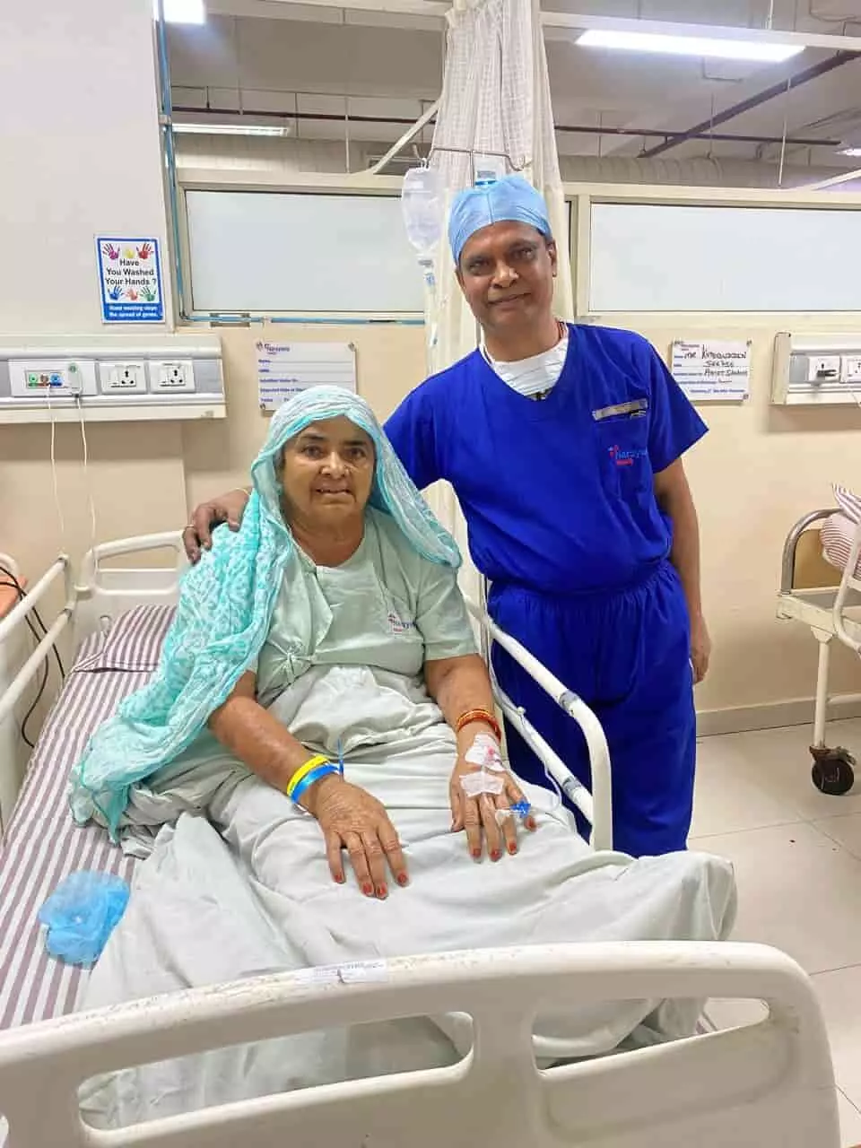 अस्पताल के बिस्तर पर बैठी मरीज और उनके बगल में खड़े डॉक्टर विजय शर्मा।