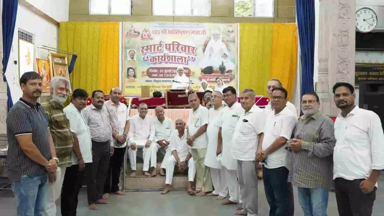तस्वीर में स्मार्ट परिवार कार्यशाला के मंच के सामने खड़े होकर समूह में पोज देते पुरुष। तस्वीर में स्मार्ट परिवार कार्यशाला के मंच के सामने खड़े होकर समूह में पोज देते पुरुष।