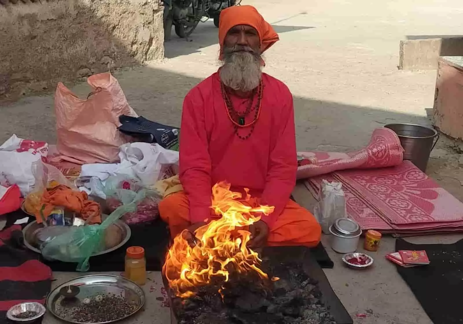 तस्वीर में नारंगी वस्त्र पहने एक साधु बारां में बारिश के लिए यज्ञ कर रहे हैं।