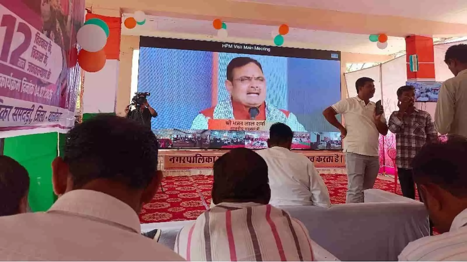 तस्वीर में एक बड़े पर्दे पर मुख्यमंत्री भजनलाल शर्मा को संबोधन करते हुए देखा जा सकता है। तस्वीर में एक बड़े पर्दे पर मुख्यमंत्री भजनलाल शर्मा को संबोधन करते हुए देखा जा सकता है।