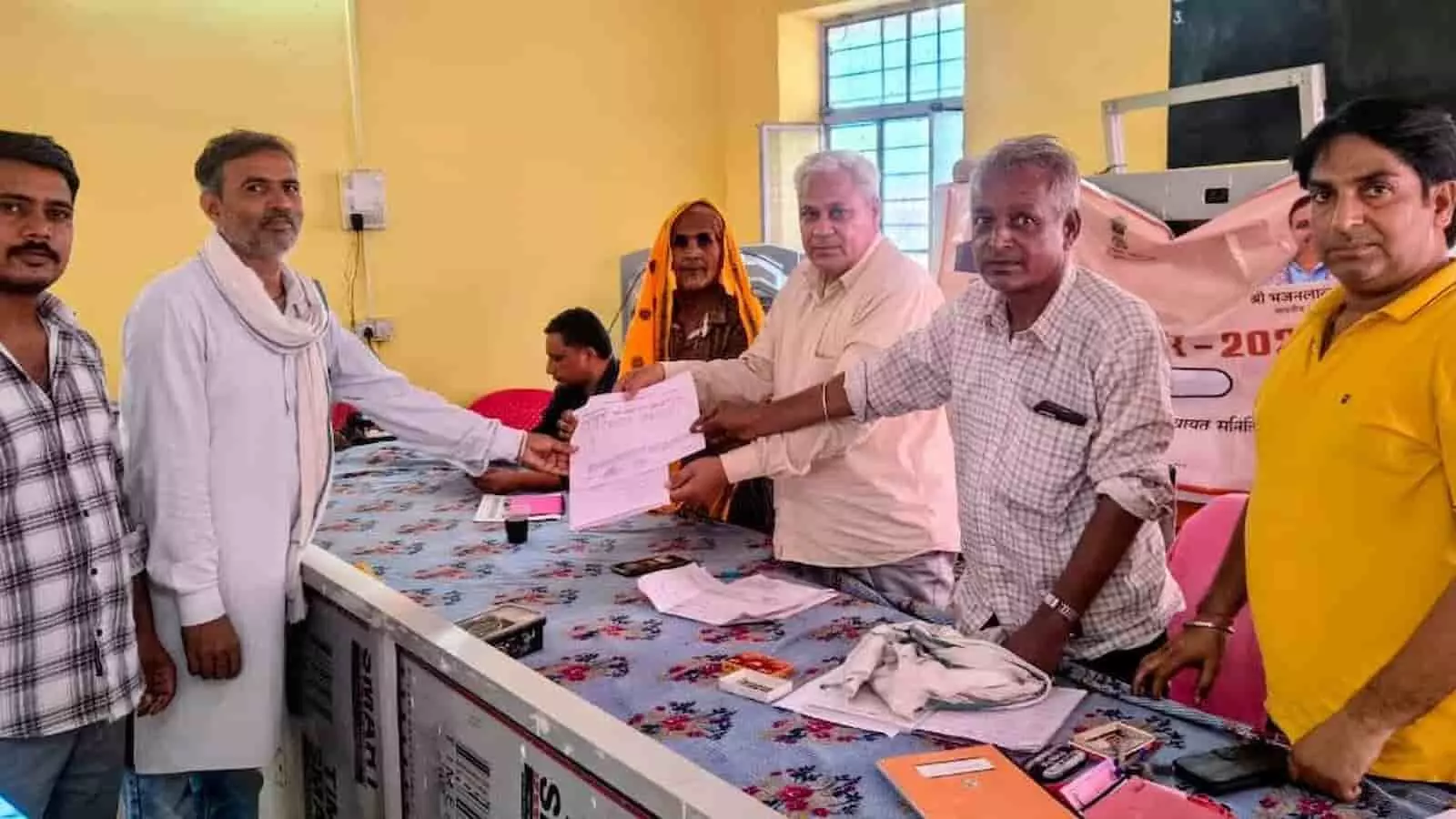 सवाई माधोपुर में ग्रामीण सेवा शिविर में अधिकारी किसान को दस्तावेज देते हुए।