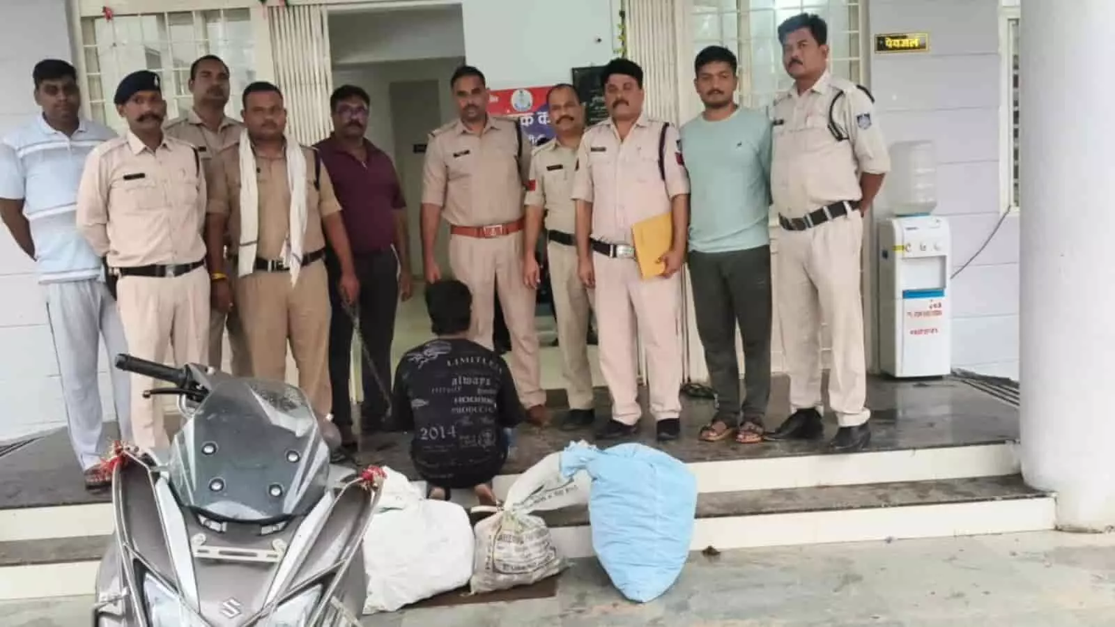 रीठी थाना परिसर के बाहर पुलिस कर्मियों के साथ खड़ा आरोपी और जब्त शराब की बोरियां।