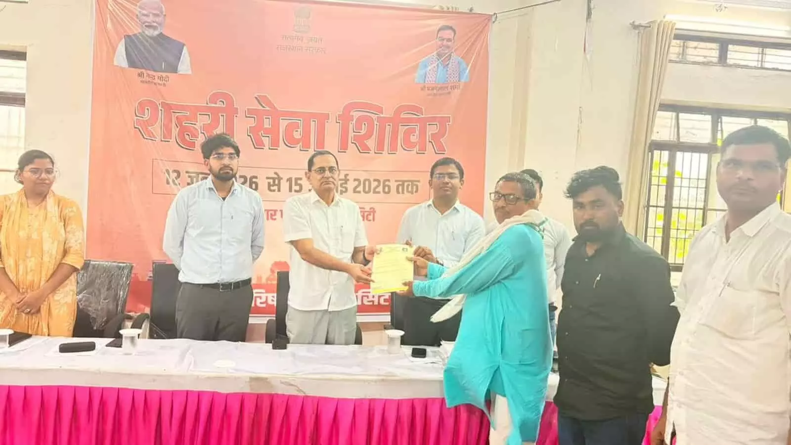 गंगापुर सिटी नगर परिषद सभागार में अधिकारी लाभार्थी को पट्टा प्रदान कर रहे हैं।