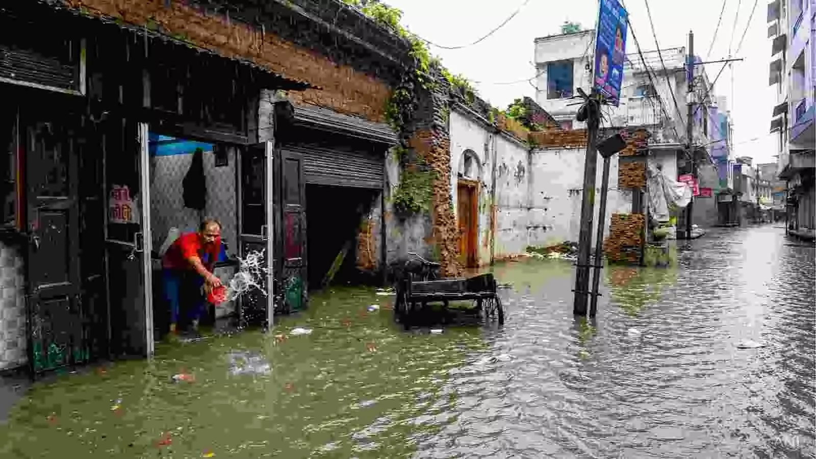 गलियों में जलभराव के बीच एक व्यक्ति उत्तर भारत में भारी बारिश के संदर्भ में।