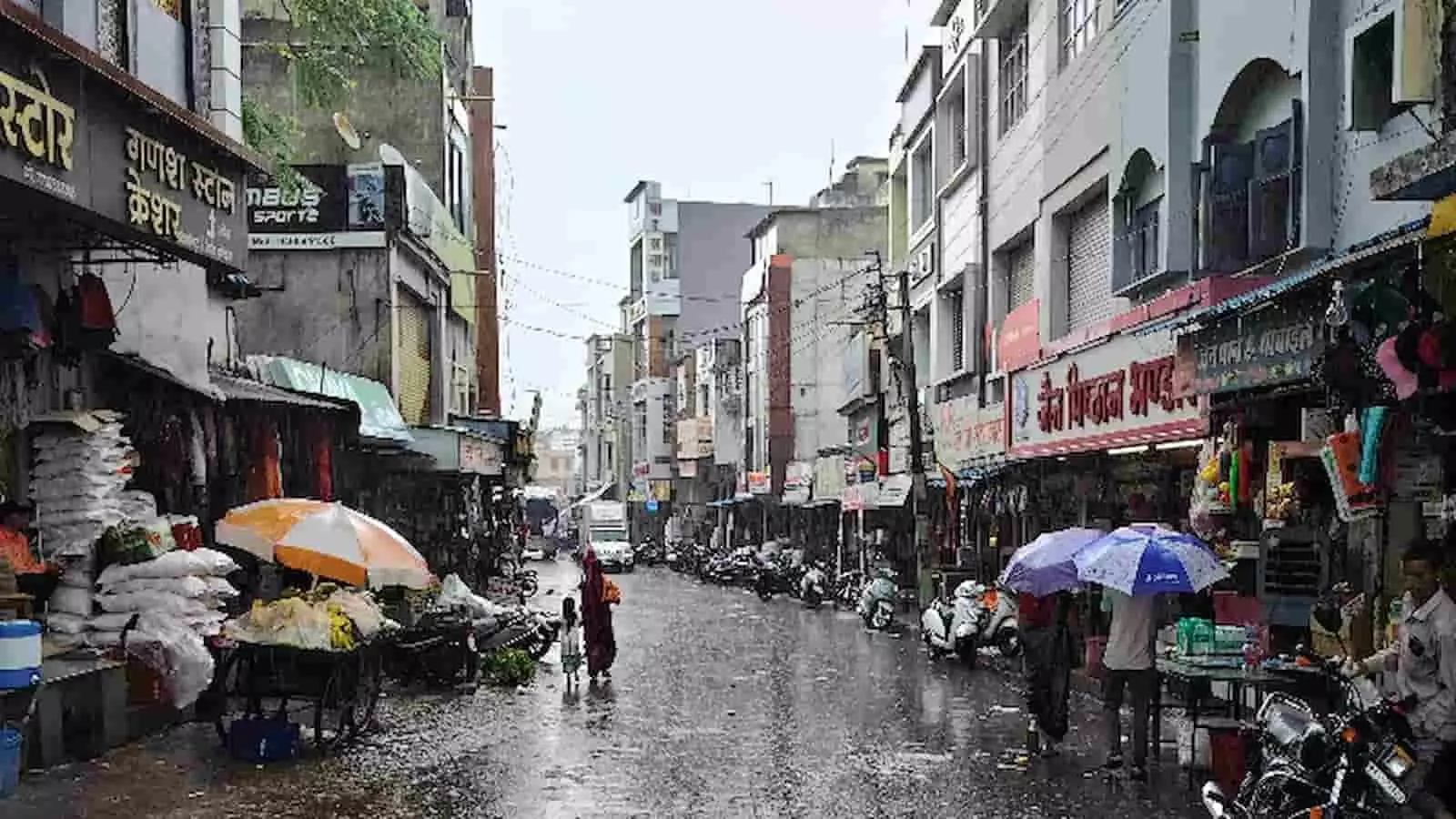 खेरवाड़ा की बारिश से भीगी सड़क पर जलभराव और छाता लिए लोग दिख रहे हैं। खेरवाड़ा की बारिश से भीगी सड़क पर जलभराव और छाता लिए लोग दिख रहे हैं।