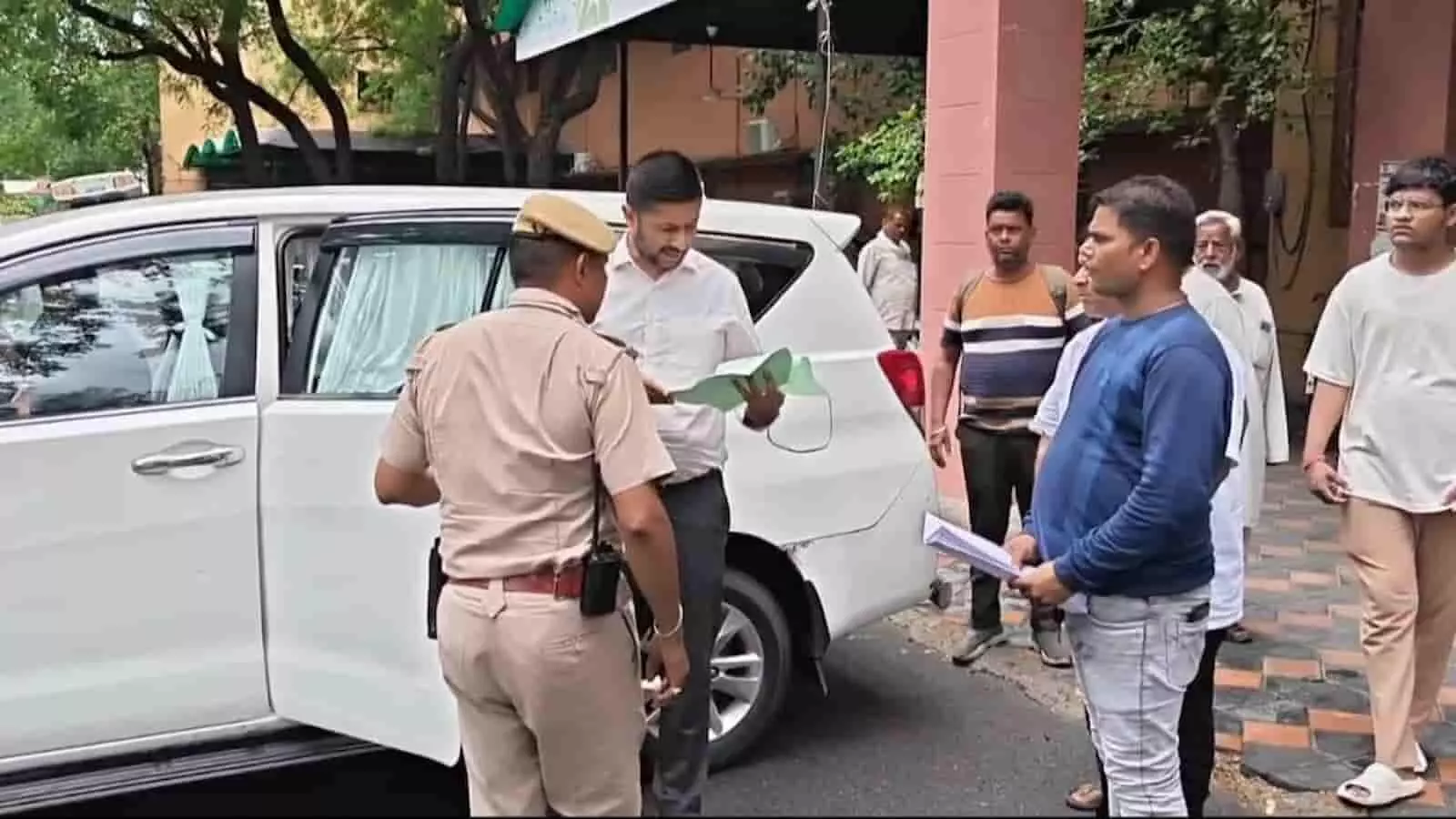 तस्वीर में एक पुलिसकर्मी और नागरिक गाड़ी के पास दस्तावेज देखते हुए शाहपुरा में नजर आ रहे हैं।