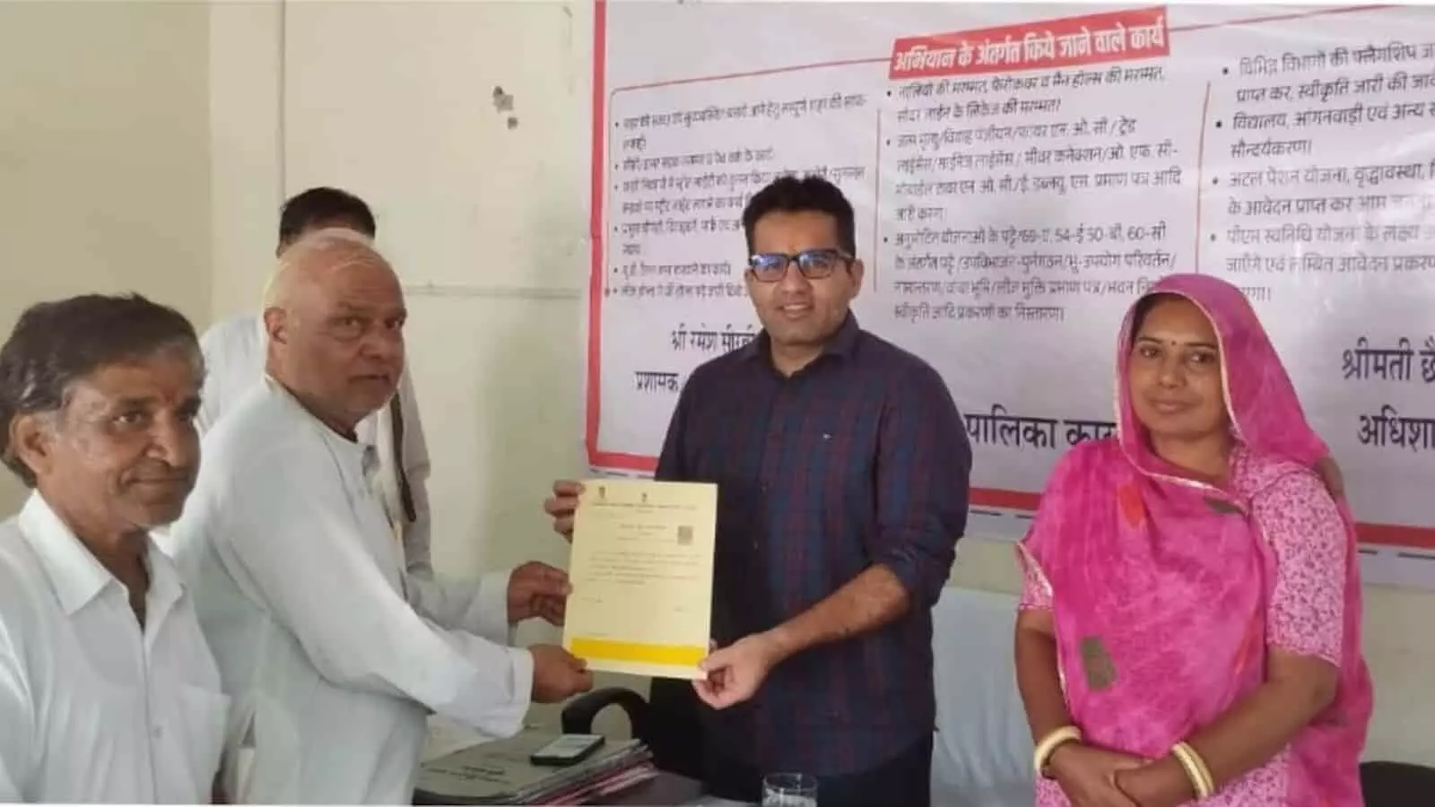 शिविर में एक अधिकारी नागरिक को दस्तावेज सौंपते हुए नजर आ रहे हैं।