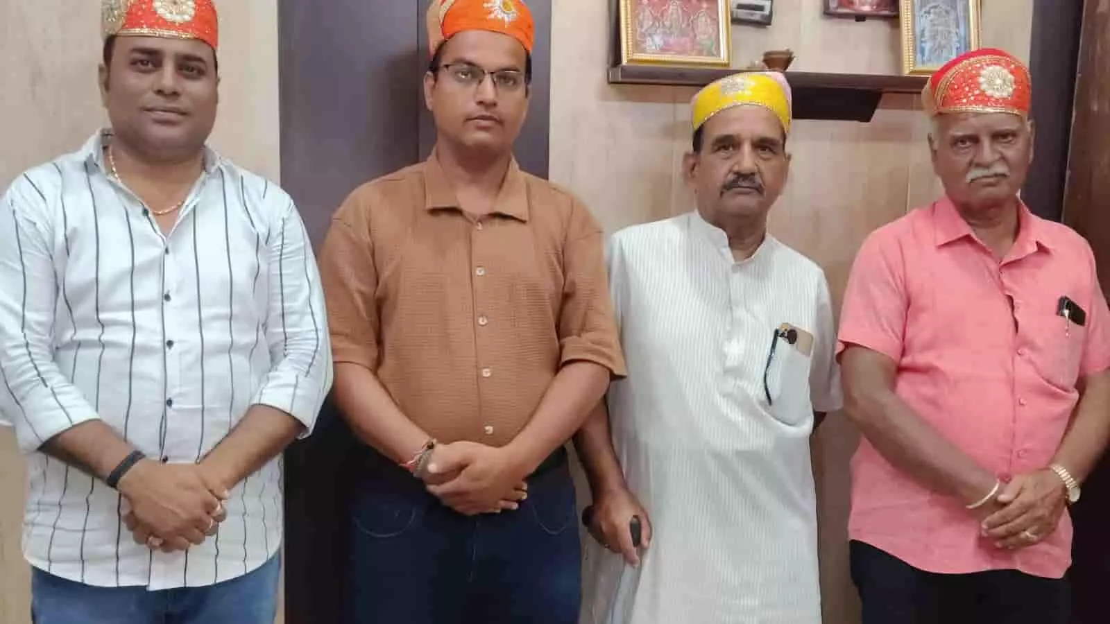 एक कमरे में पारंपरिक टोपी पहने सीधे खड़े राजस्थान नगरपालिका कर्मचारी फैडरेशन के चार पदाधिकारी।