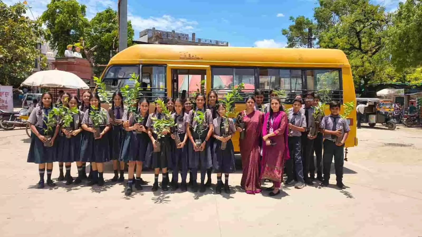 बेगूं में स्कूल यूनिफॉर्म पहने विद्यार्थी और शिक्षक हाथ में पौधे लिए खड़े हैं।
