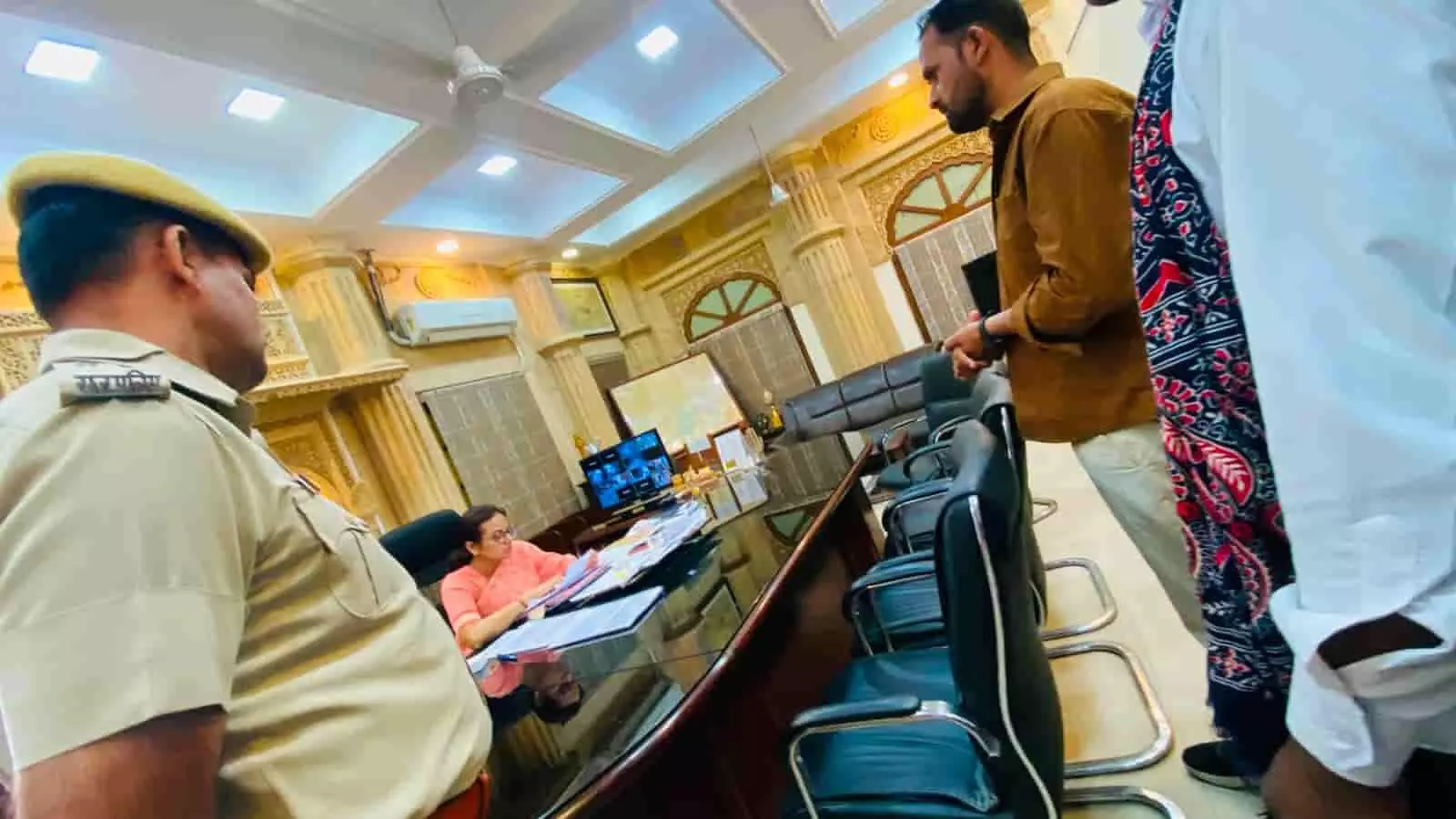 कार्यालय की मेज पर कागजात देखती महिला अधिकारी और उनके सामने खड़े पुलिसकर्मी व ग्रामीण।