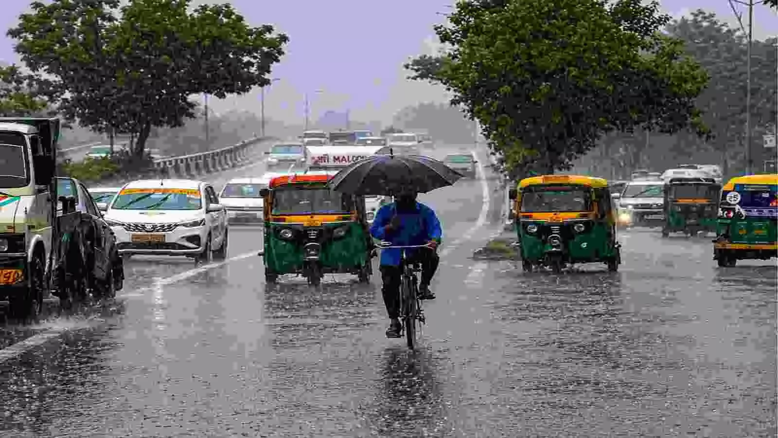 बारिश के दौरान सड़क पर साइकिल चलाते व्यक्ति और वाहनों का दृश्य।