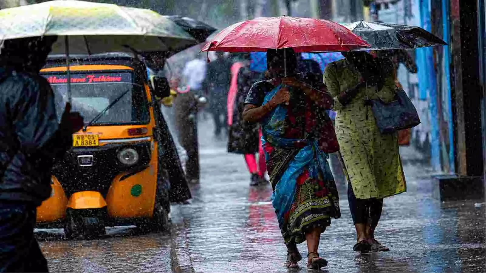 बारिश में छाता लेकर सड़क पार करती महिलाएं दक्षिण भारत के संदर्भ में।