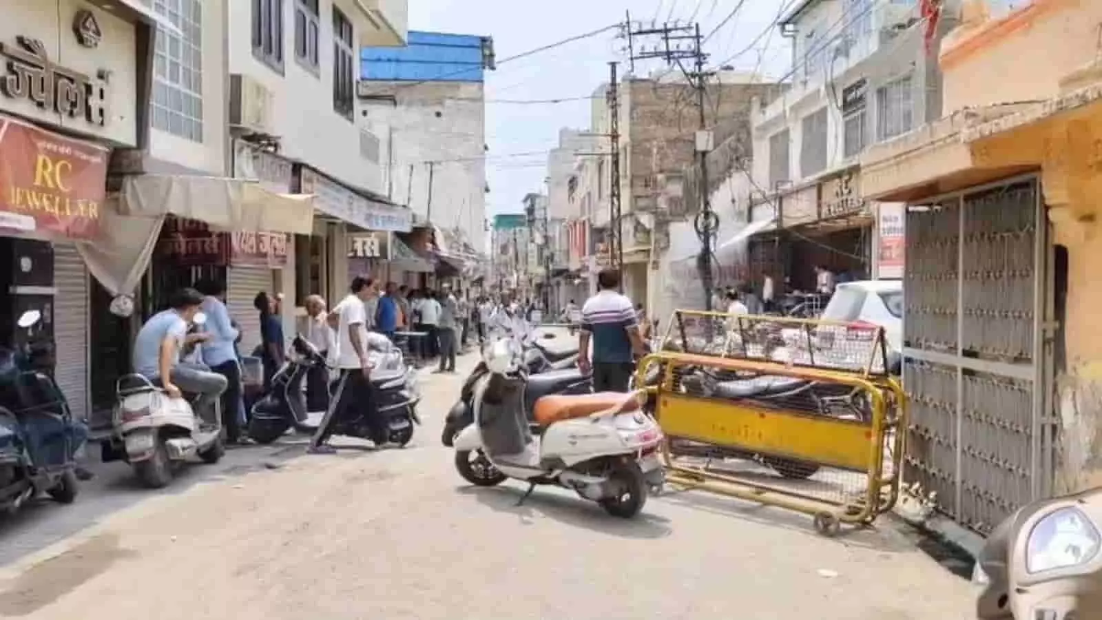 भीलवाड़ा सराफा बाजार मार्ग पर बैरिकेड्स के पास खड़े लोग और खड़े दोपहिया वाहन। भीलवाड़ा सराफा बाजार मार्ग पर बैरिकेड्स के पास खड़े लोग और खड़े दोपहिया वाहन।