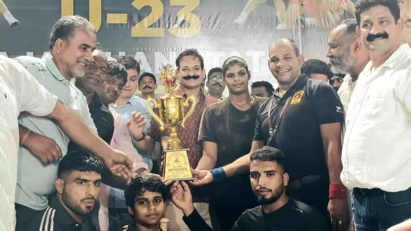 तस्वीर में राज्य स्तरीय कुश्ती प्रतियोगिता के विजेता पहलवान और अधिकारी मंच पर चमचमाती ट्रॉफी थामे दिख रहे हैं। तस्वीर में राज्य स्तरीय कुश्ती प्रतियोगिता के विजेता पहलवान और अधिकारी मंच पर चमचमाती ट्रॉफी थामे दिख रहे हैं।