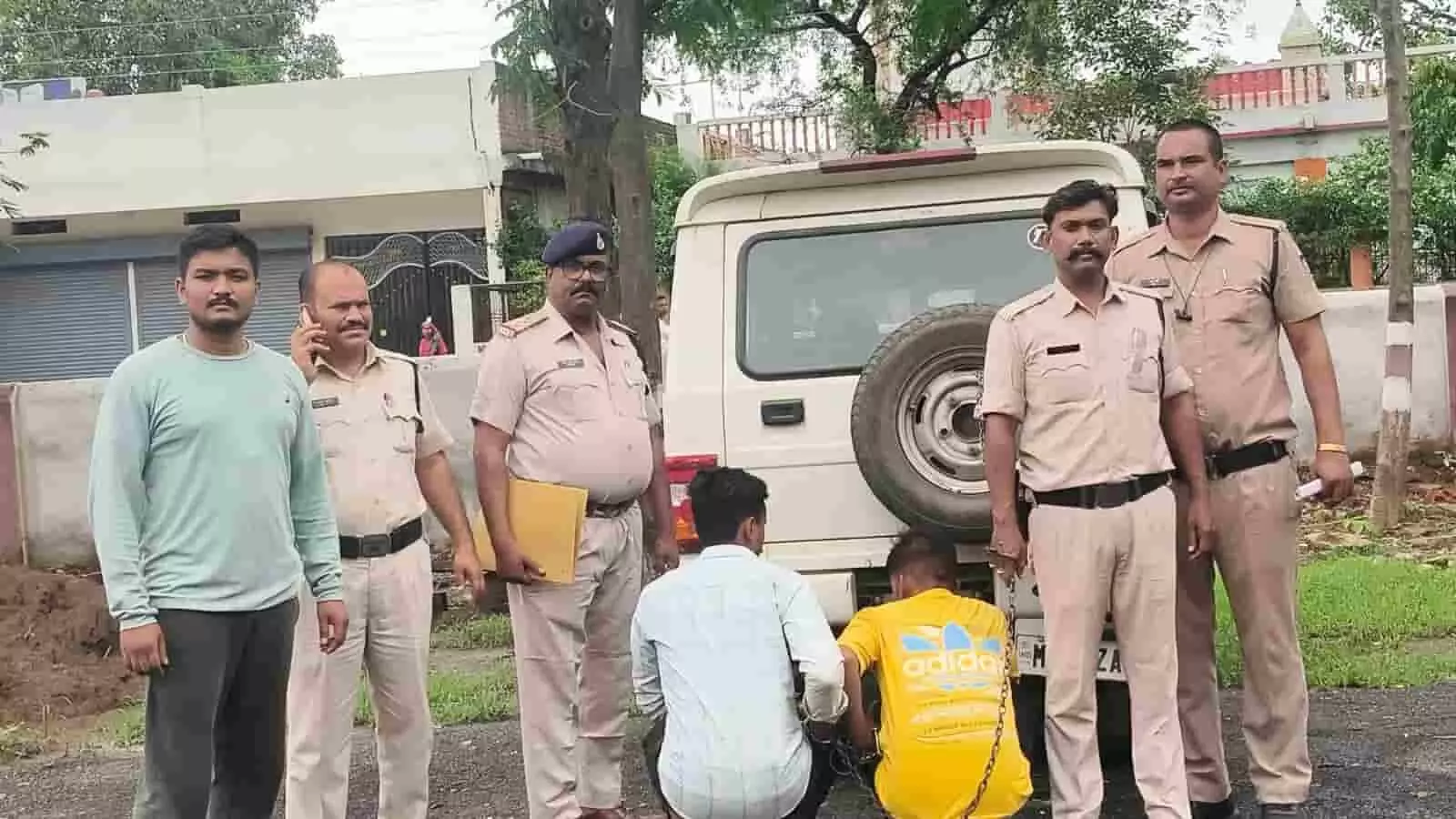 तस्वीर में सफेद वाहन के सामने खड़े पुलिसकर्मी और जमीन पर बैठे दो आरोपी पुलिस कार्रवाई के संदर्भ में दिख रहे हैं। तस्वीर में सफेद वाहन के सामने खड़े पुलिसकर्मी और जमीन पर बैठे दो आरोपी पुलिस कार्रवाई के संदर्भ में दिख रहे हैं।