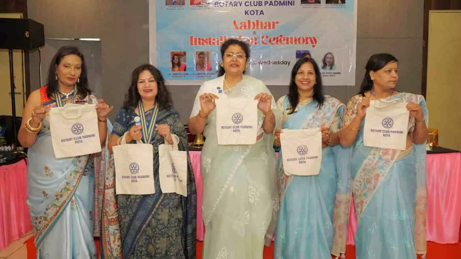 रोटरी क्लब पद्मिनी कोटा के समारोह में कपड़े के थैले हाथ में लिए मंच पर खड़ीं महिला सदस्य। रोटरी क्लब पद्मिनी कोटा के समारोह में कपड़े के थैले हाथ में लिए मंच पर खड़ीं महिला सदस्य।