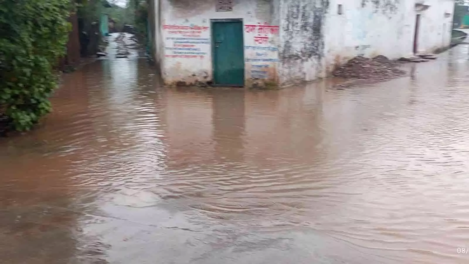 तस्वीर में जलभराव से घिरी सड़क और मकान दिख रहे हैं जहां बारिश का पानी जमा है। तस्वीर में जलभराव से घिरी सड़क और मकान दिख रहे हैं जहां बारिश का पानी जमा है।