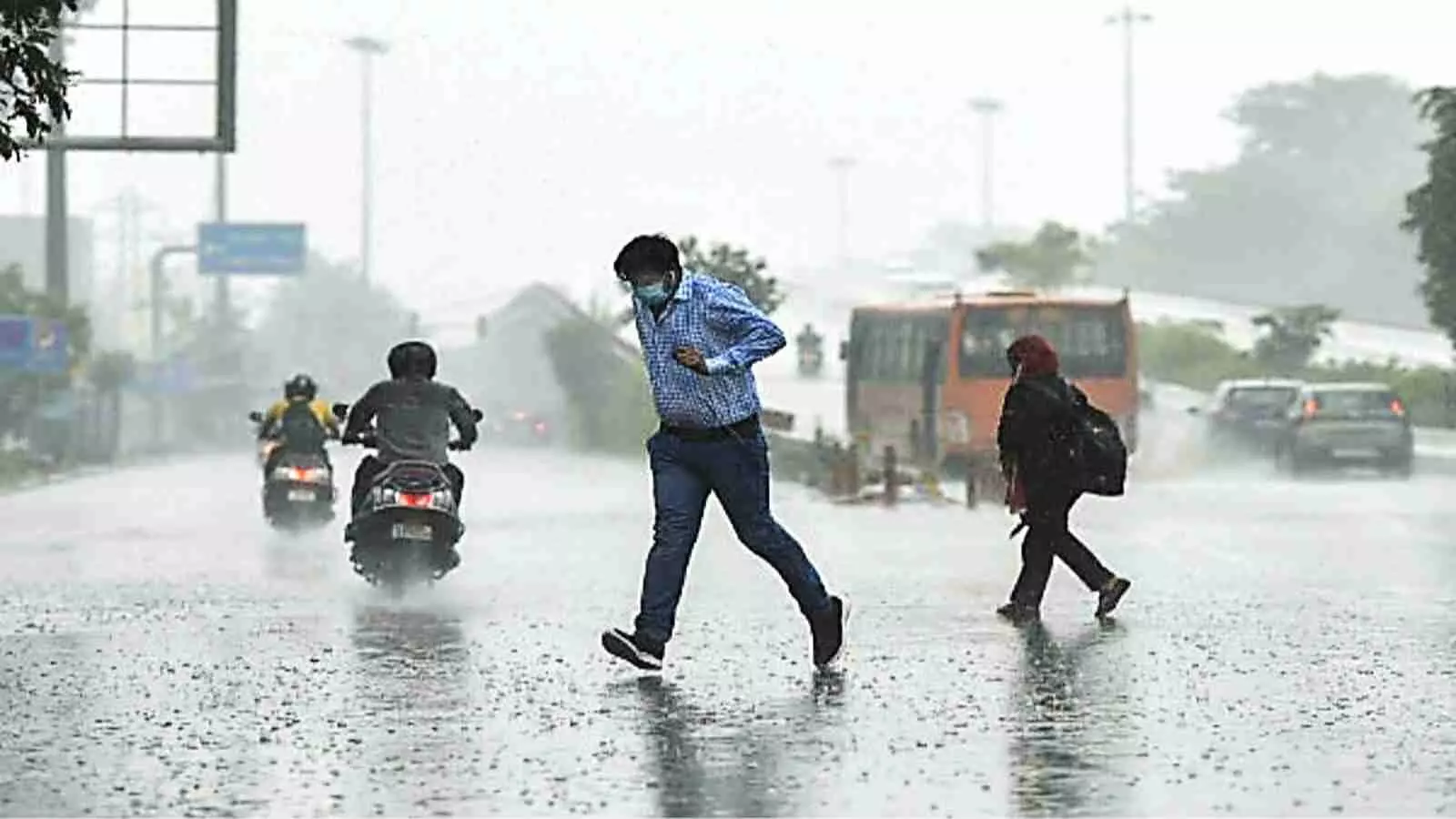 बारिश के दौरान सड़क पर चलते लोग और वाहन दक्षिण भारत में मानसून का दृश्य।