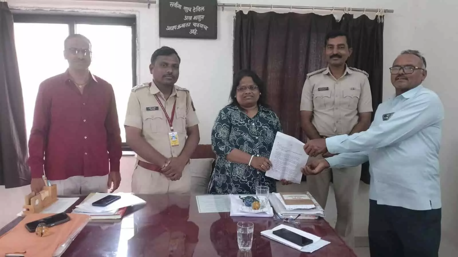 कार्यालय कक्ष में मेज के पास खड़े ग्रामीण और अधिकारी ज्ञापन सौंपने के दौरान। कार्यालय कक्ष में मेज के पास खड़े ग्रामीण और अधिकारी ज्ञापन सौंपने के दौरान।