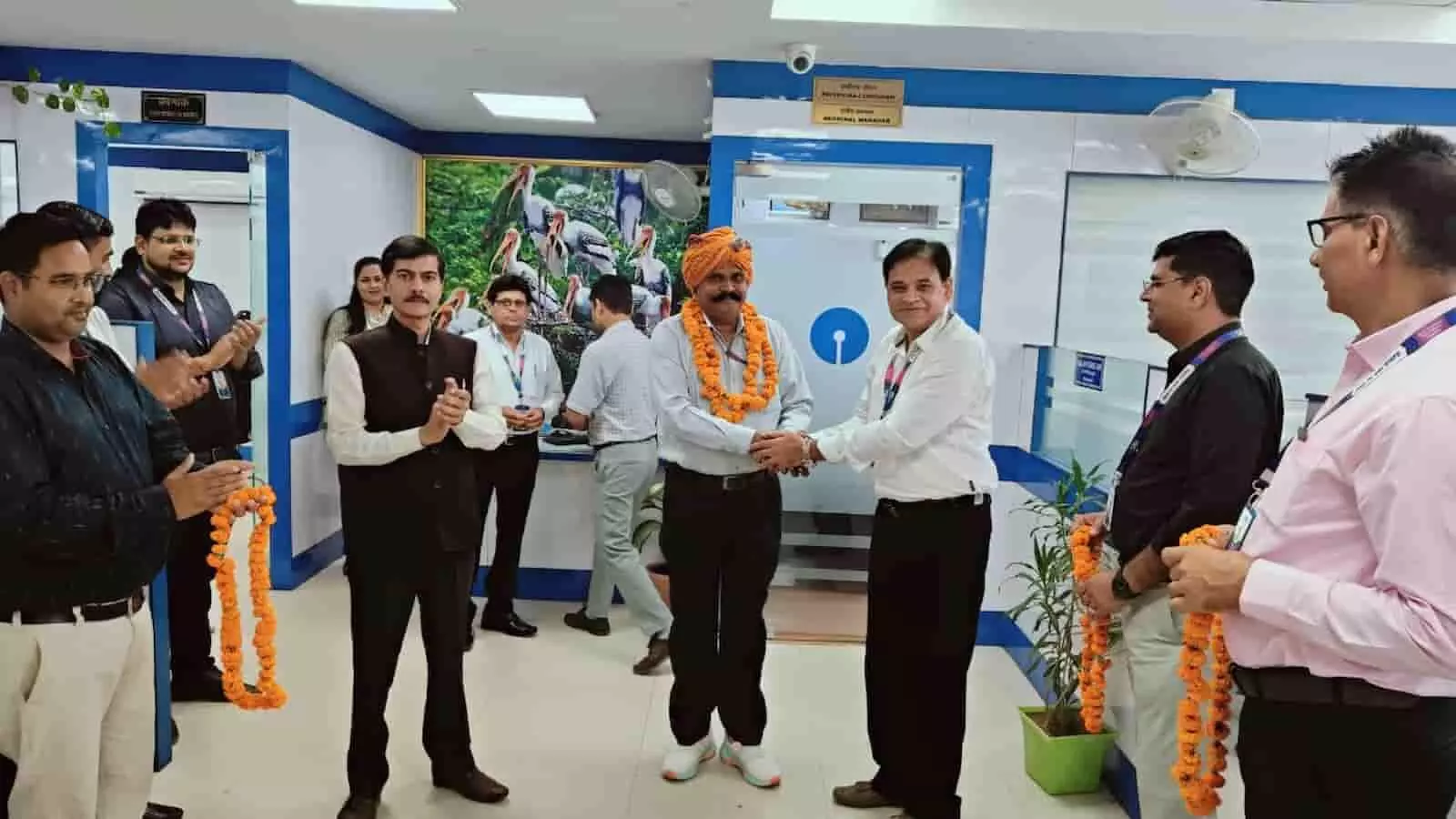 तस्वीर में एसबीआई बैंक शाखा के अंदर अधिकारी द्वारा गार्ड कर्तार सिंह को सम्मानित करते हुए दिखाया गया है। तस्वीर में एसबीआई बैंक शाखा के अंदर अधिकारी द्वारा गार्ड कर्तार सिंह को सम्मानित करते हुए दिखाया गया है।